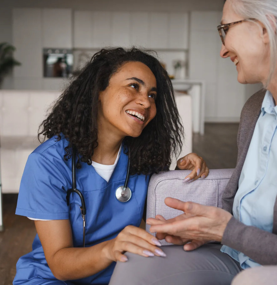 A nurse smiling and talking with a woman in a living room